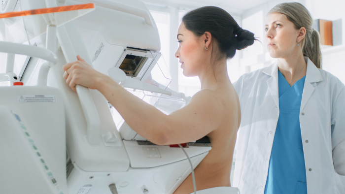 Woman receiving a mammogram with mammography tech in background