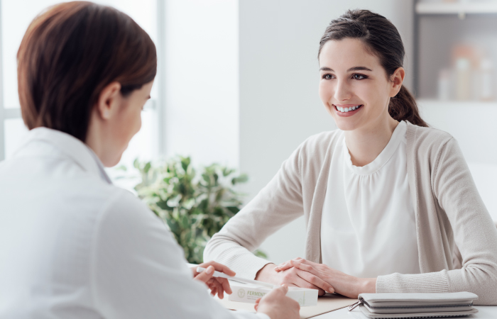 Provider and smiling female patient sit at table  