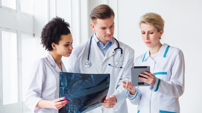 Three physicians consulting over an xray