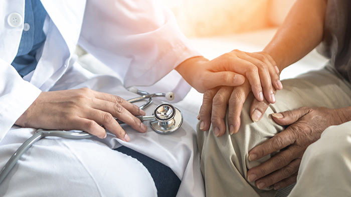 Doctor in white coat holding patients hand