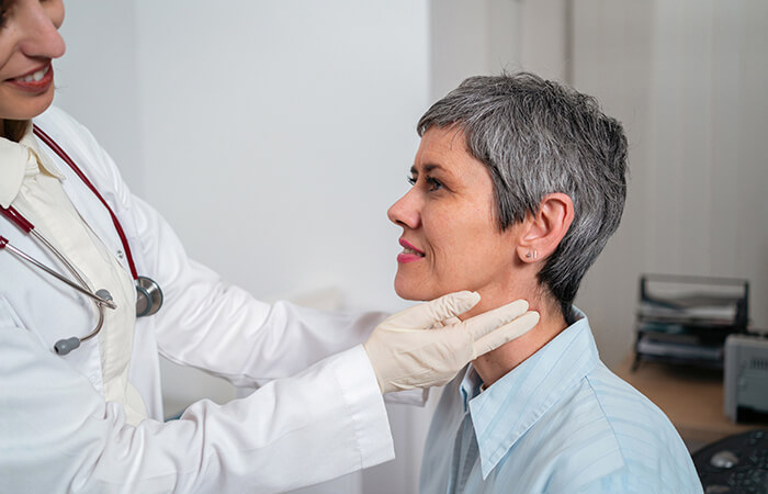 mature woman having her thyroid checked by a black female doctor