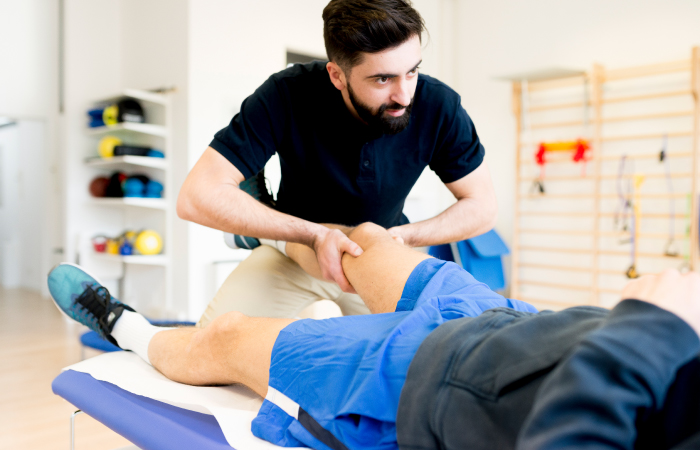Male physical therapist doing knee exercises with a older male patient
