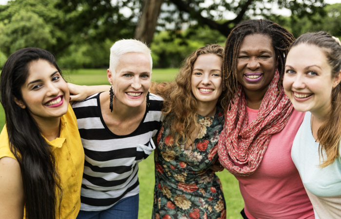 Four women standing next to each other posing and smiling at the camera