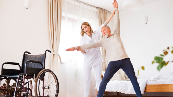 Home Care nurse helping senior male patient with physical rehabilitation