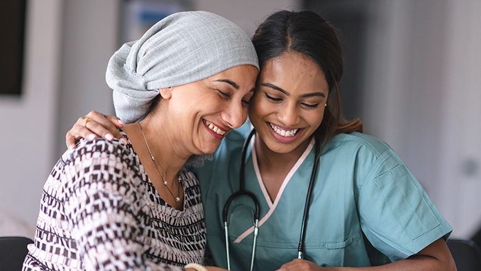 Female cancer patient leaning on female nurse