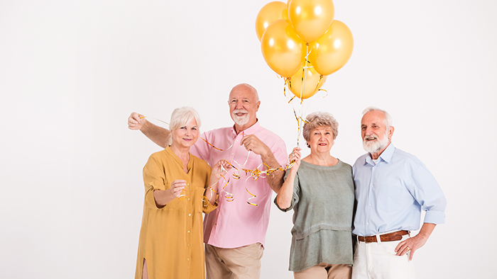 two older couples holding bouquet of balloons