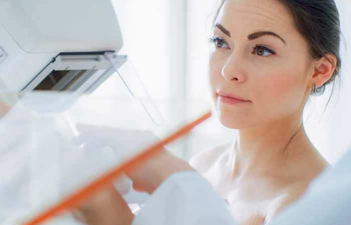 Closeup of woman standing in front of mammogram machine
