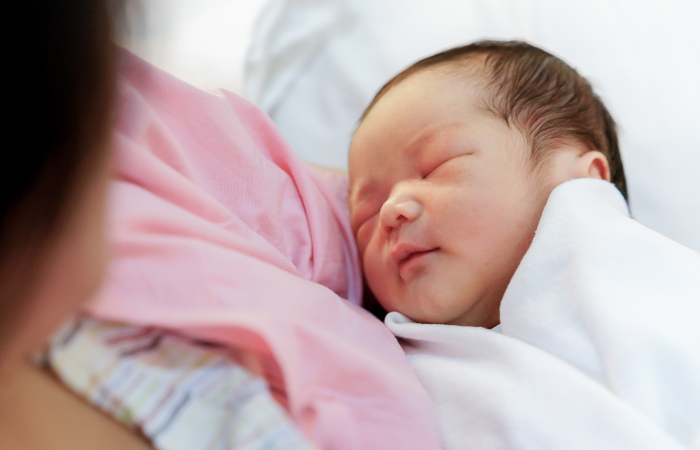 Mother holding newborn baby wrapped in blanket