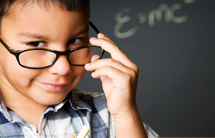 young child holding glasses down and looking into camera