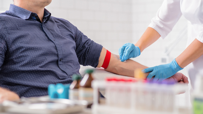 Technician performing a blood draw on a young man