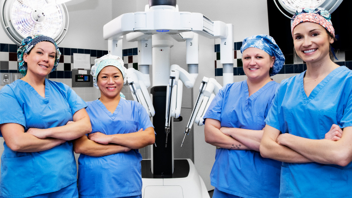 Four nurses gather around DaVinci robotic surgery system