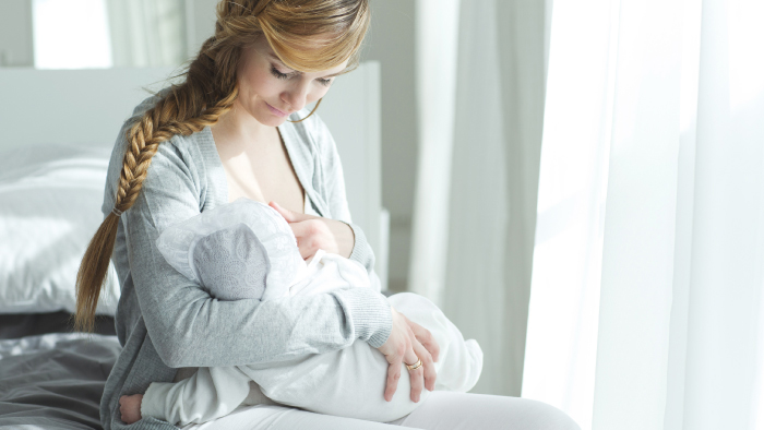 Infant baby breastfeeding in mom's arms