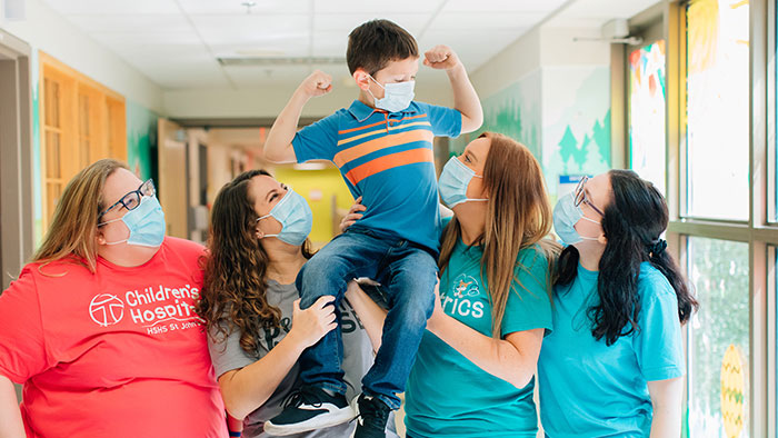 Group of nursing staff holding boy on shoulders