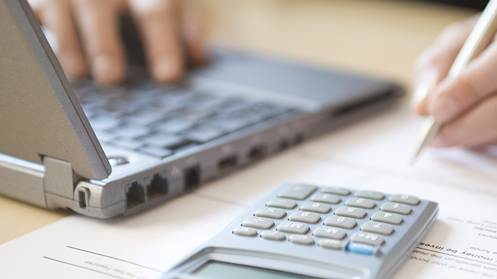 Hands working with laptop and calculator