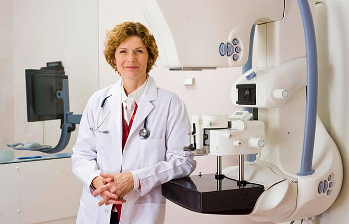 Female clinician assists women while getting a mammogram