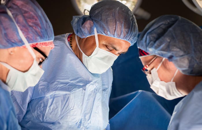 group of surgeons performing a surgery in full PPE