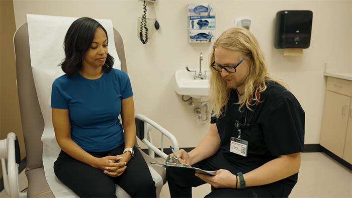 medical assistant writing down information on clipboard with patient