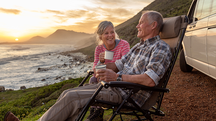 Retired couple sitting in front of their RV looking out at the coast