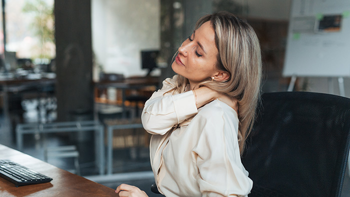 woman holding neck at desk