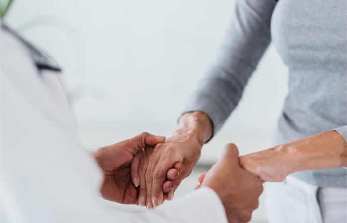 Doctor taking patients hands into both of their hands