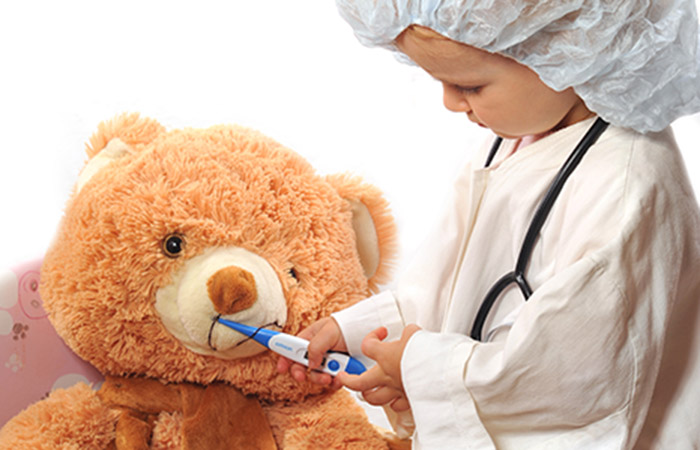 Orange teddy bear getting his temperature taken by a child dressed as a doctor