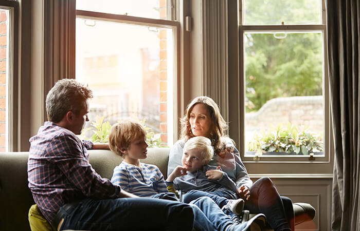 2 parents sitting on the couch with a toddler and a child