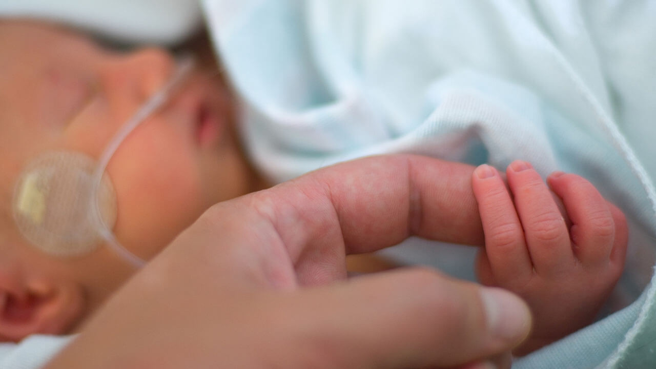 Mother holding a premature baby's hand