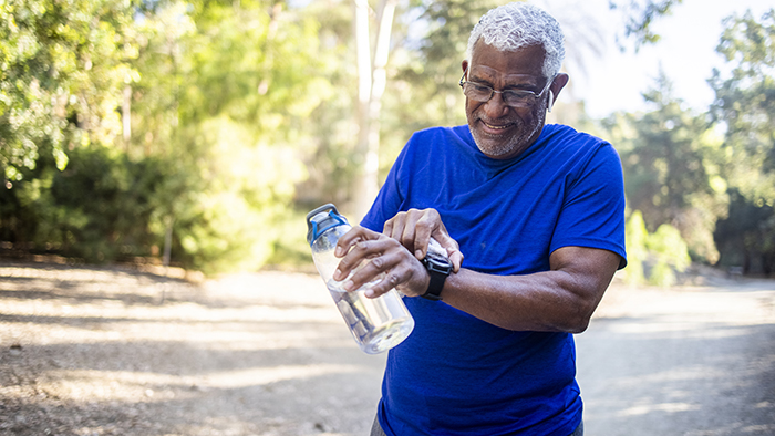 A senior man checking his fitness watch on a walk outdoores