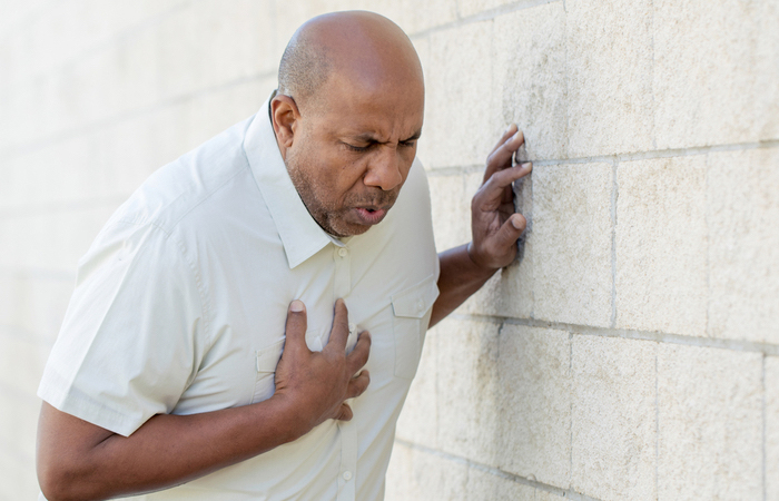 middle aged man grabbing chest while having a heart attack