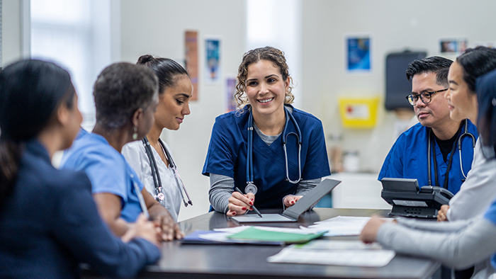 A young nurse leads a discussion with other health care professionals