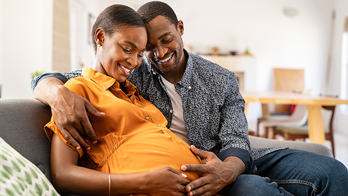 Young couple on the couch admiring pregnant belly