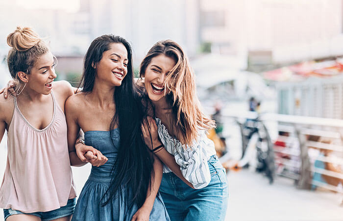 group of three teen girls walking down the street laughing and smiling