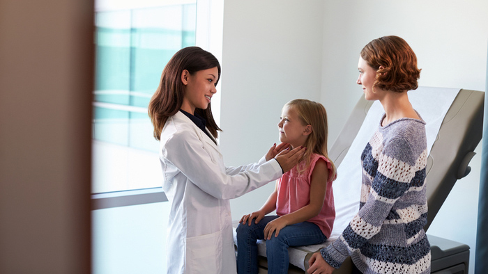 Femail doctor checking little girl with mom by her side