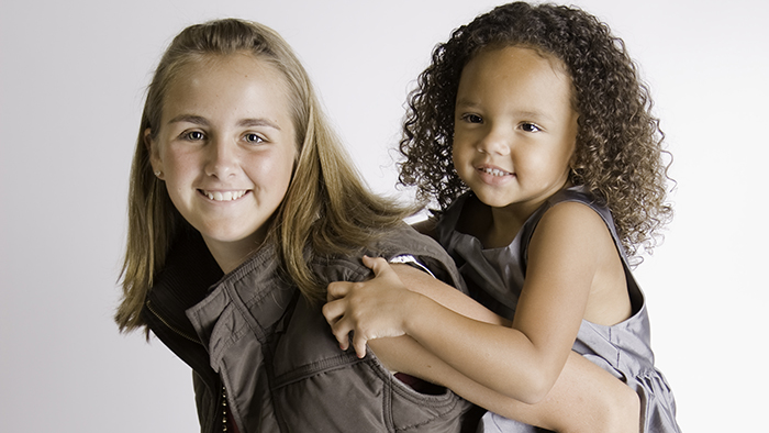 Young girl babysitter holding smaller child 