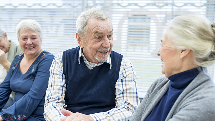 Older man in blue vest taking with an older woman