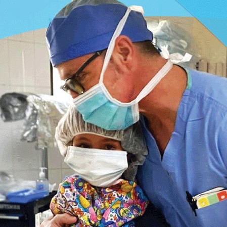 A surgeon hugs a female child to comfort her before her surgery