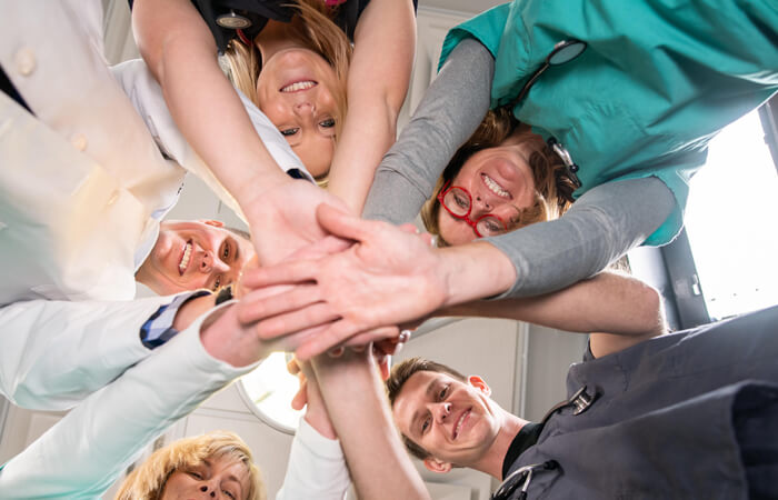 Group of physicians and providers coming together and putting their hands in a circle