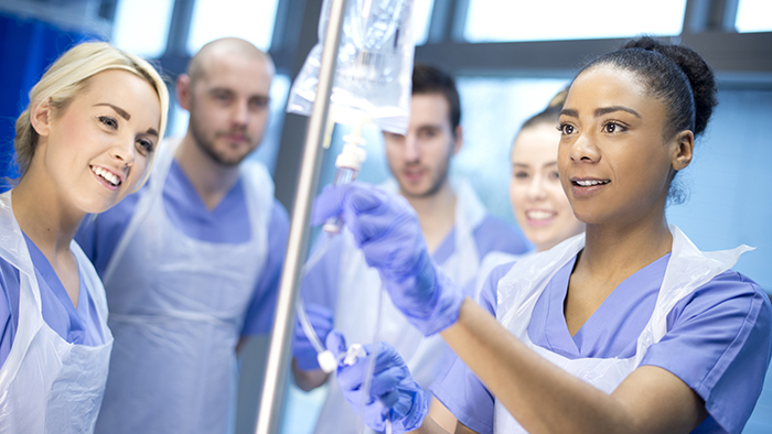 Five young nursing students practicing with an IV 