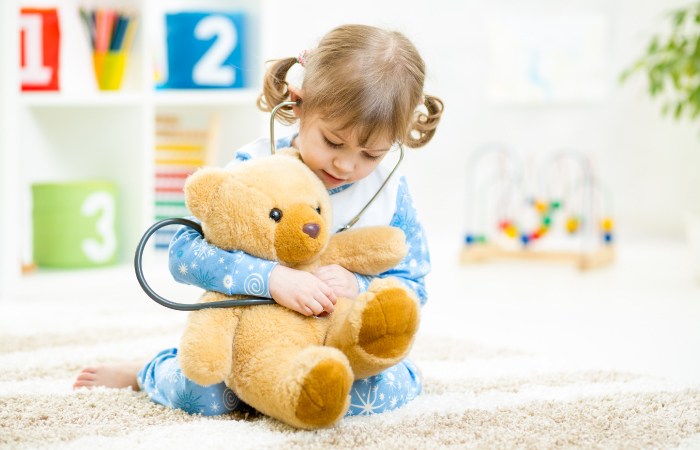 A little girl uses a stethoscope to listen to her teddy bear's heart beat.