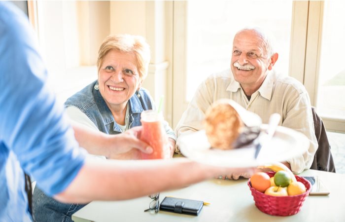 Female patient in hospital room smiling and looking at her colorful meal