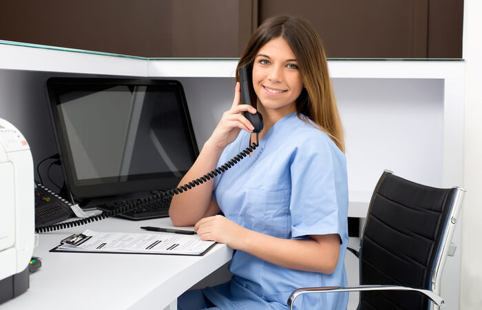 Brunette white woman in a cubicle smiling while on the phone