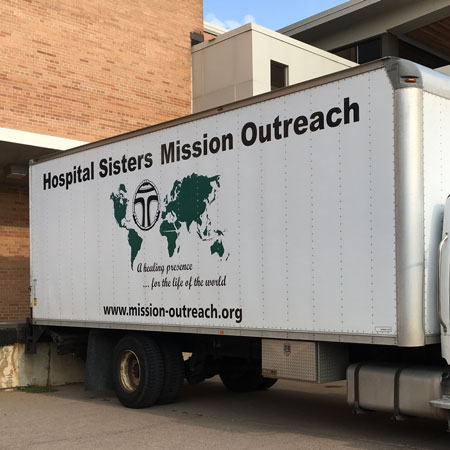 A Mission Outreach truck backs up to a loading dock