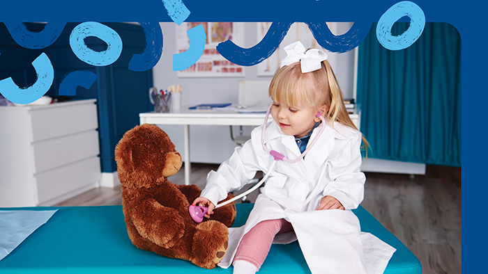 Young girl dressed as doctor with teddy bear