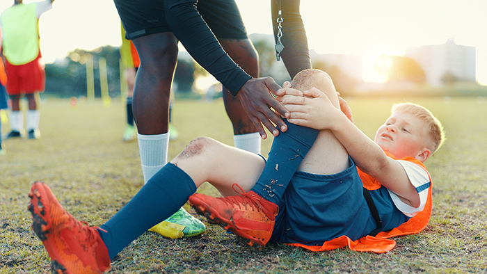 young boy holding shin on soccer field