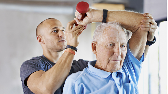 Male therapist assisting senior male patient with exercises