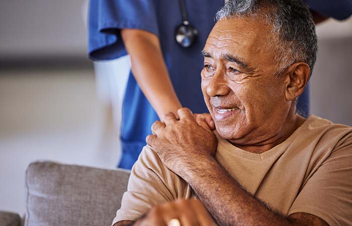 elderly hispanic man with nurses hand on his shoulder