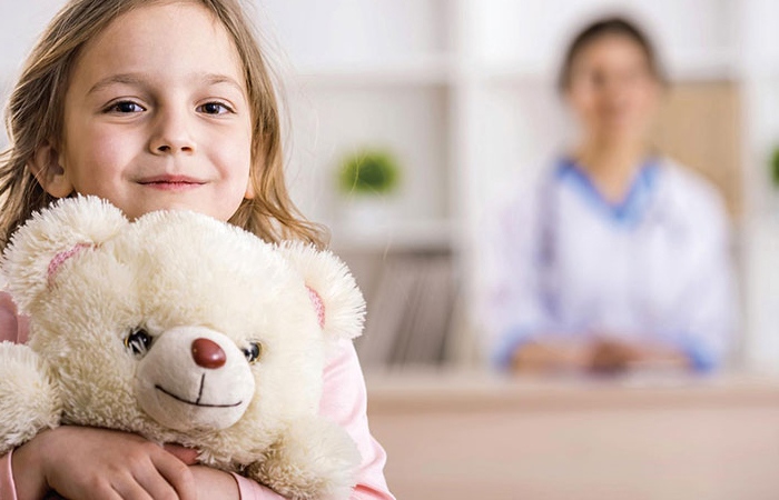 young girl smiling and holding a teddy bear