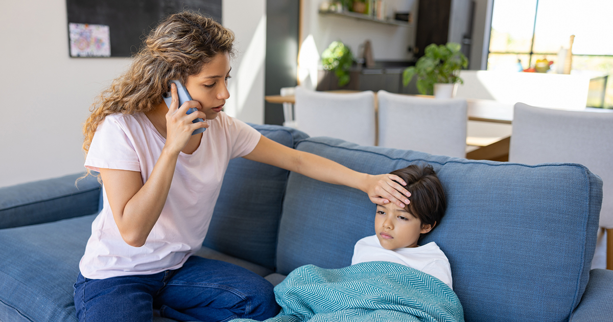 mother checking childs temperature while on the phone