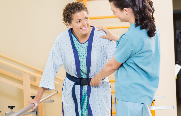Young female nurse assisting young female patient with mobility rehabilitation