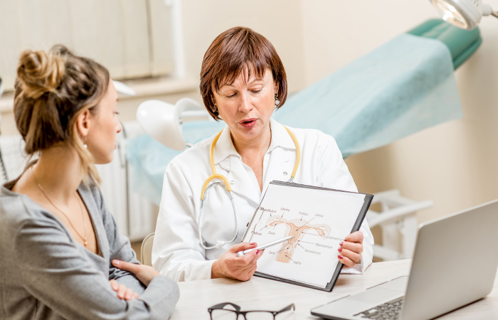 Female doctor pointing at a diagram of a uterus while young woman observes